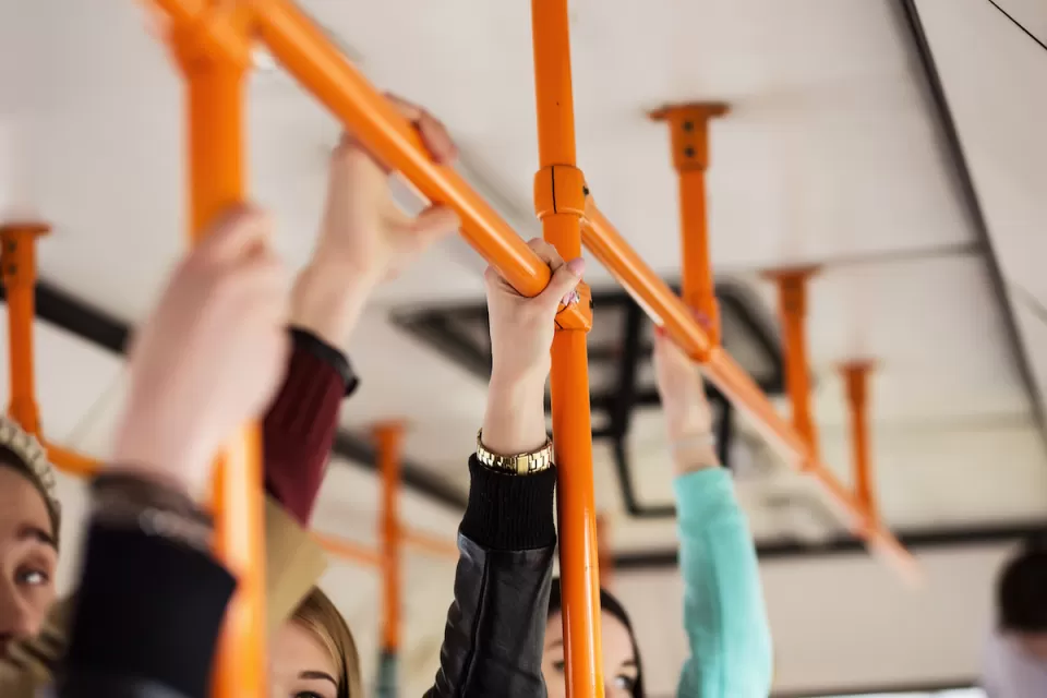 Close-up of hands holding straps on public bus.